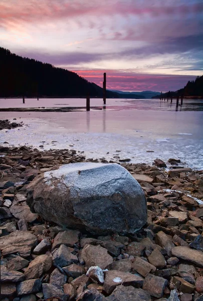 Gün batımında göl kenarında büyük kaya. — Stok fotoğraf