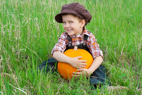 Smiling boy with pumpkin on the grass — Stock Photo, Image
