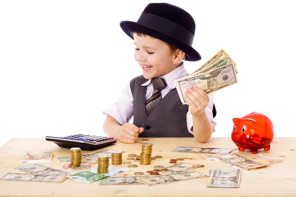 Мальчик за столом считает деньги Лицензионные Стоковые Фото