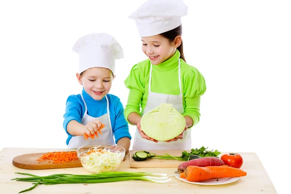 Двое улыбающихся детей готовят салат — стоковое фото