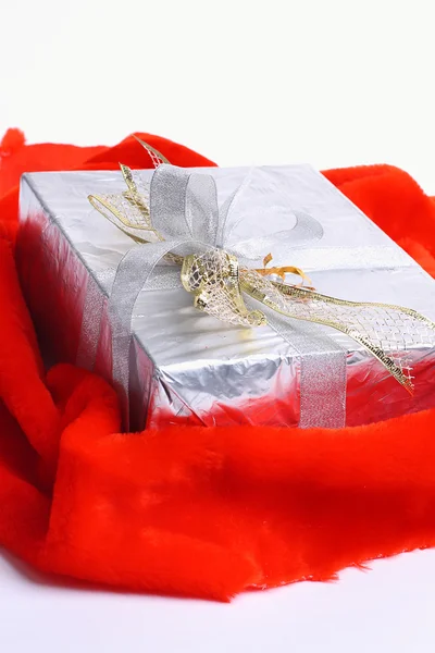 Подарункова коробка з червоною стрічкою на червоній тканині, на білому тлі . — стокове фото