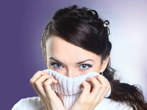 Beautiful girl in sweater buries her face. Isolated on a purple background. — Stock Photo, Image