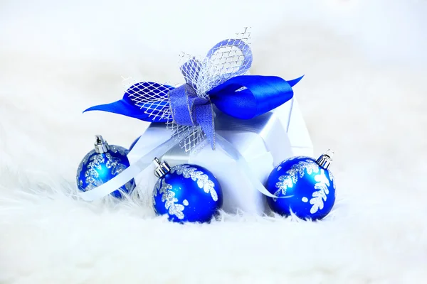 Festive balls with gift box on snow — Stock Photo, Image