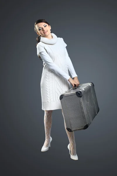 Ein schönes Mädchen mit einem Koffer in der Hand. isoliert auf grauem Hintergrund — Stockfoto