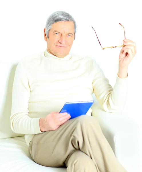 Hombre mayor relajándose en casa con un libro — Foto de Stock