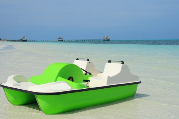 Paddle boat on beach by ocean — Stock Photo, Image