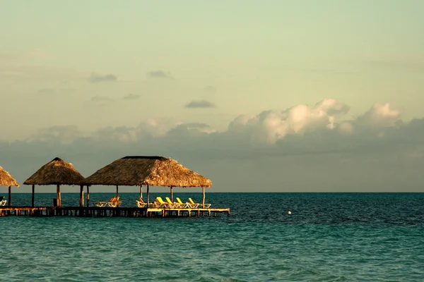 Dok i krzesła w popołudniowym słońcu przez ocean — Zdjęcie stockowe