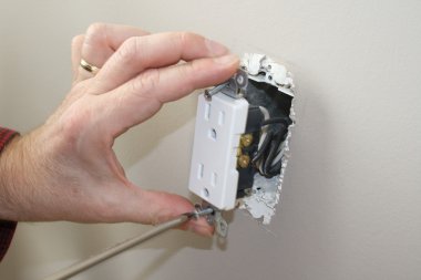 Qualified electrician removing a power outlet for testing clipart