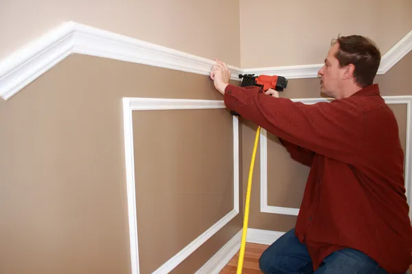 Carpinteiro profissional instalando trilho de cadeira wainscotting e guarnição de paredes para renovação de casa — Fotografia de Stock