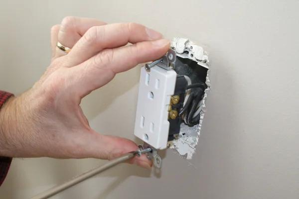 Szakképzett villanyszerelővel eltávolítása egy konnektorba vizsgálatához Stock Kép