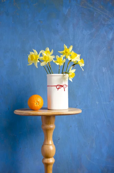 Bouquet narcissus in vase and orange fruit — Stock Photo, Image