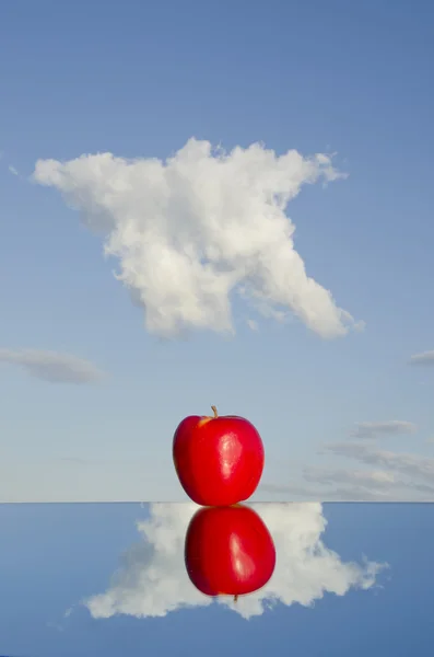 Červené jablko na zrcadlo a mraky — Stock fotografie