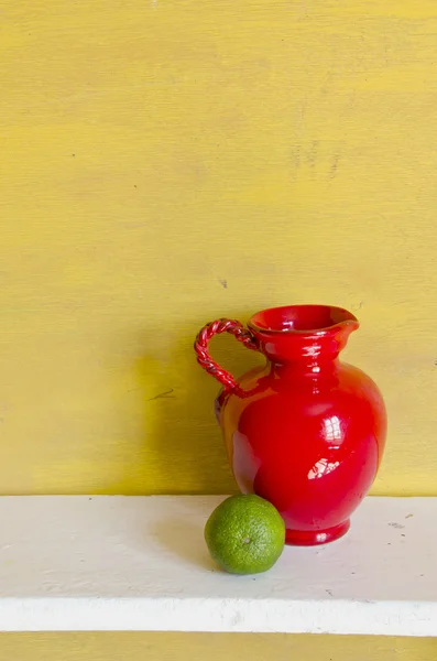 Red jug and green lemon — Stock Photo, Image