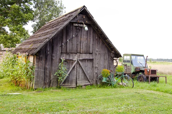 Oude boerderij houten gebouw en gebroken trekker — Stockfoto