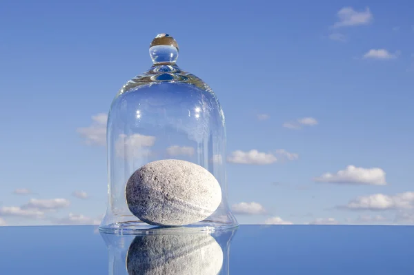 Стеклянный объект с камнем на зеркале — стоковое фото