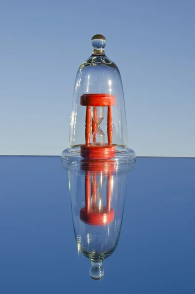 Sandglass vermelho no frasco de vidro e espelho — Fotografia de Stock