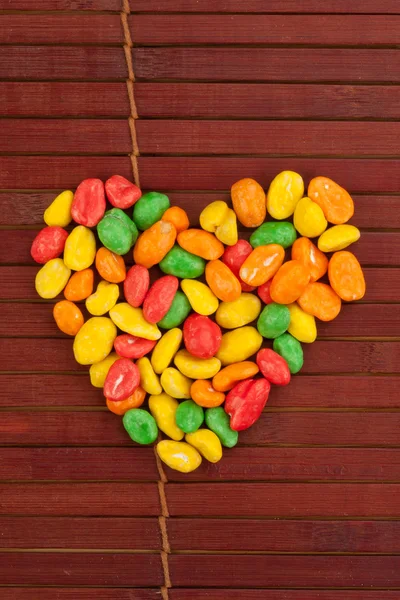 Dragees coloridos de amendoim dispostos em forma de coração — Fotografia de Stock