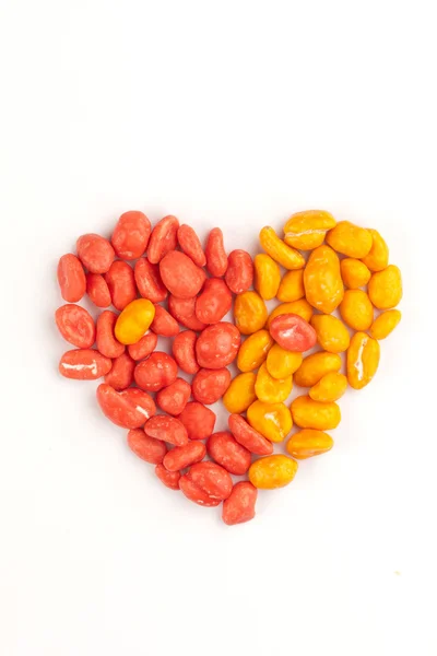 Rote und gelbe Dragees aus Erdnüssen in Herzform — Stockfoto