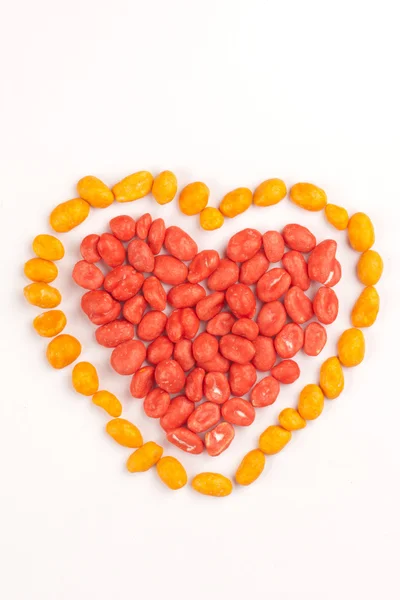 Red heart and yellow contour made of dragees of peanuts — Stock Photo, Image