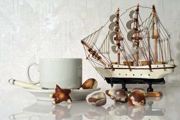 Натюрморт с чашкой, конфетами и яхтой — стоковое фото