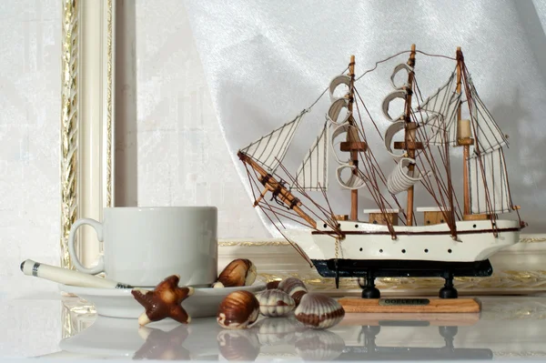 Натюрморт с чашкой, конфетами и яхтой — стоковое фото
