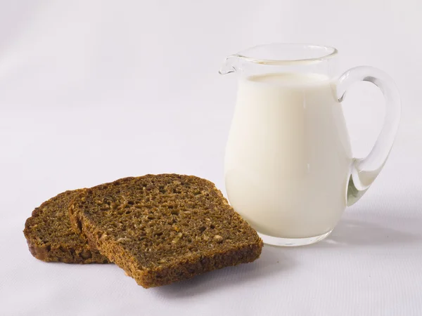 Jarra de leche y rebanadas de pan de centeno — Foto de Stock