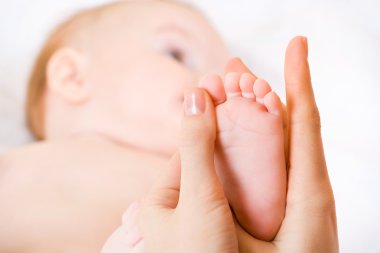 Mother massaging her child's foot, shallow focus clipart