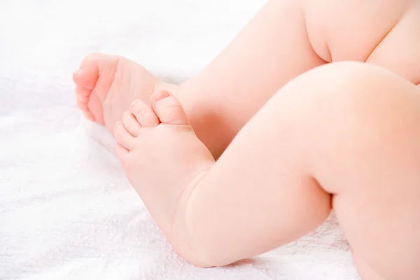 Ноги ребенка крупным планом на белом одеяле — стоковое фото