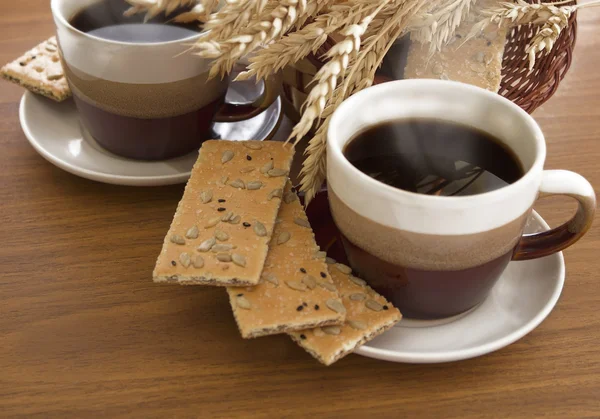 Two cups of coffee and basket with wheat and cookies — Stock Photo, Image