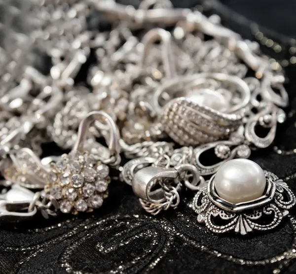 Különböző ezüst, csillogó ékszerek és a vértes a fekete gyöngy — Stock Fotó
