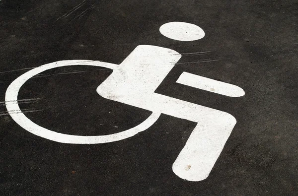 Symbolem osoby na wózku inwalidzkim, opierając się na drodze — Zdjęcie stockowe