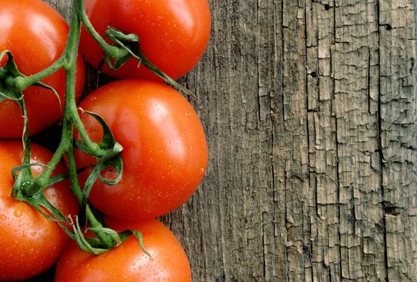Red tomatoes on the old board — Stock Photo, Image