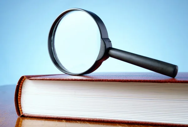 Magnifying glass and a book — Stock Photo, Image