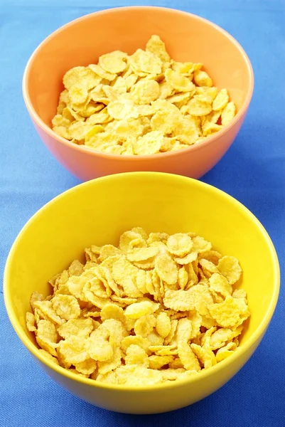 Taças amarelas e laranja com flocos de milho — Fotografia de Stock