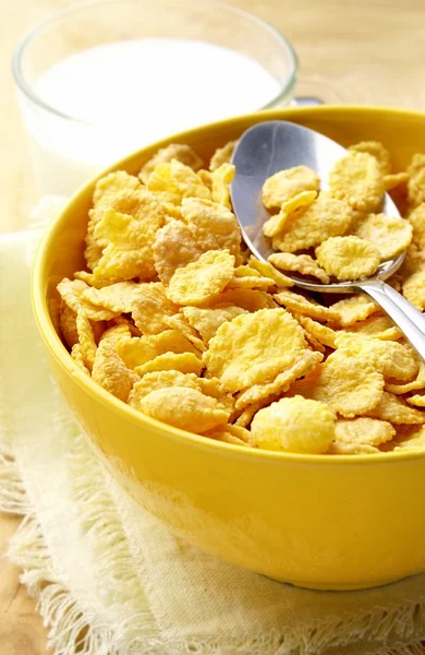 Milk in a glass cup and corn flakes in a yellow bowl — Stock Photo, Image