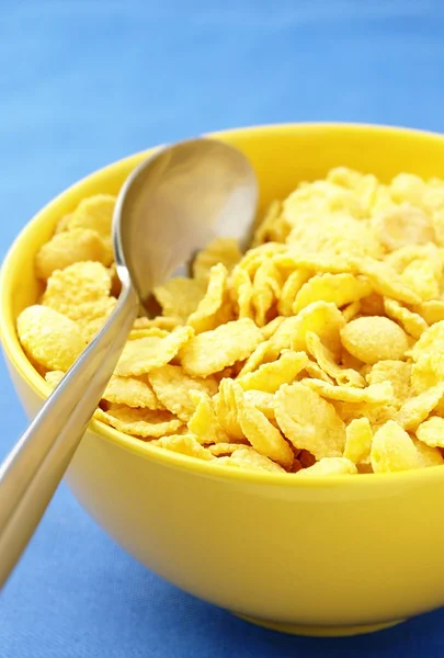 Flocons de maïs dans un bol jaune et une cuillère — Photo