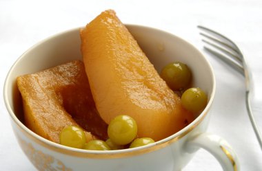 Canned pears in a bowl and fork on the table clipart