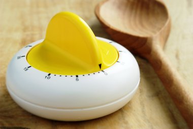 Kitchen timer and a wooden spoon on the table clipart