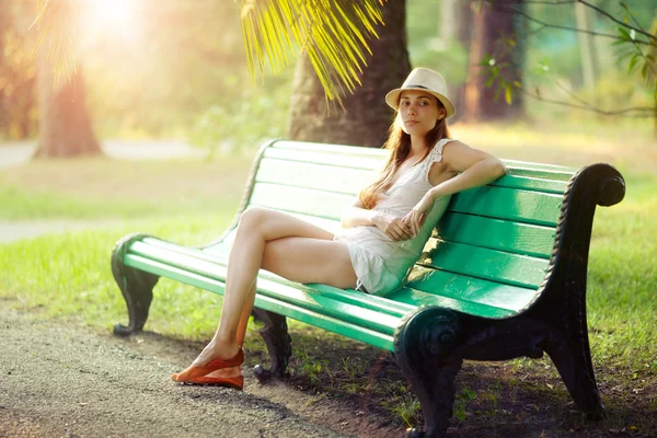 Девушка, сидящая на скамейке — стоковое фото