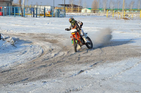 MX rider på motorcykel rör sig i en helomvändning med medar i snö Stockfoto
