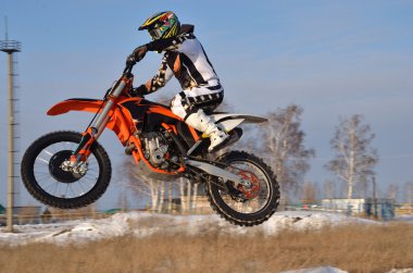 Motocross, motorcycle driver flies over hill out of snow clipart