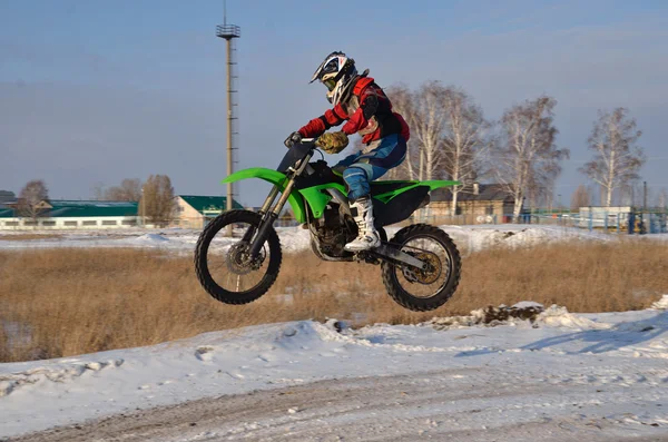 Motocross: Motorradfahrerin fliegt aus Schnee über Hügel Stockfoto