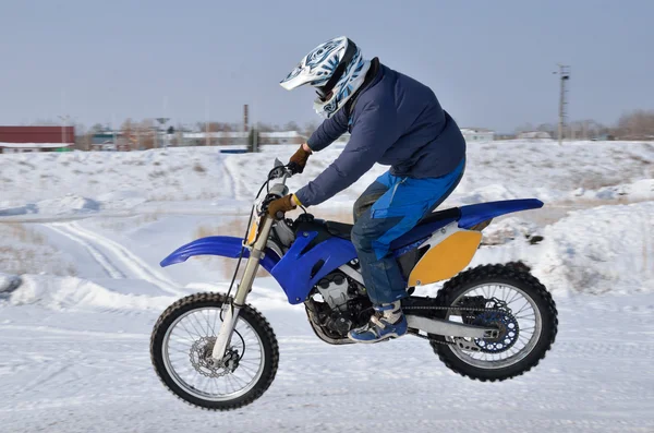 Motorcross, motorfiets stuurprogramma vliegt over heuvel uit sneeuw Rechtenvrije Stockafbeeldingen