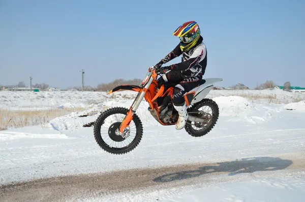 Motorcross stuurprogramma vliegt over heuvel uit sneeuw Rechtenvrije Stockfoto's