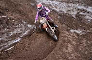 Rider at the beginning of rut turning sandy motocross track clipart