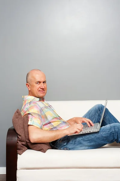Senior man thuis met laptop — Stockfoto