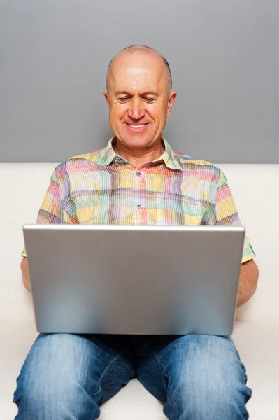 Ανώτερος άνθρωπος κάθεται με το φορητό υπολογιστή στο σπίτι — Φωτογραφία Αρχείου