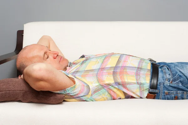 Ανώτερος άνθρωπος κοιμάται στον καναπέ λευκό — Φωτογραφία Αρχείου