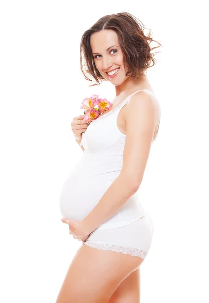 Студийный снимок улыбающейся беременной женщины с цветами — стоковое фото