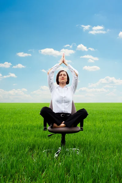 Young businesswoman practicing yoga on the meadow — Stock Photo, Image